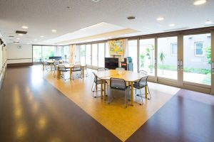 明るい共用ラウンジ。テーブルと椅子が配置され、大きな窓から採光が入る。