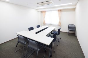 会議室またはミーティングスペース。長テーブルと椅子が配置された室内